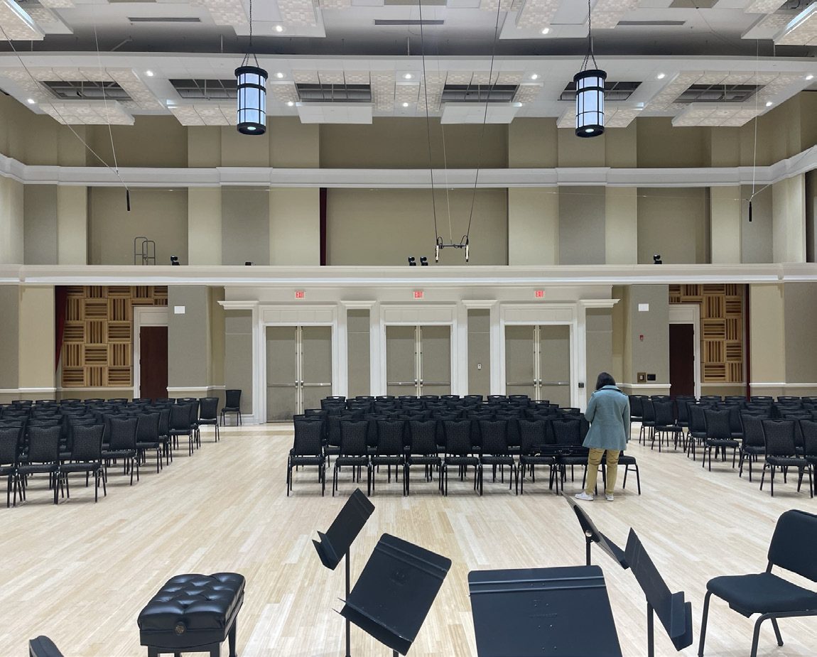 Renovated rehearsal hall with rows of chairs and music stands.